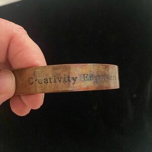 Copper bracelet, stamped with “creativity empowers”